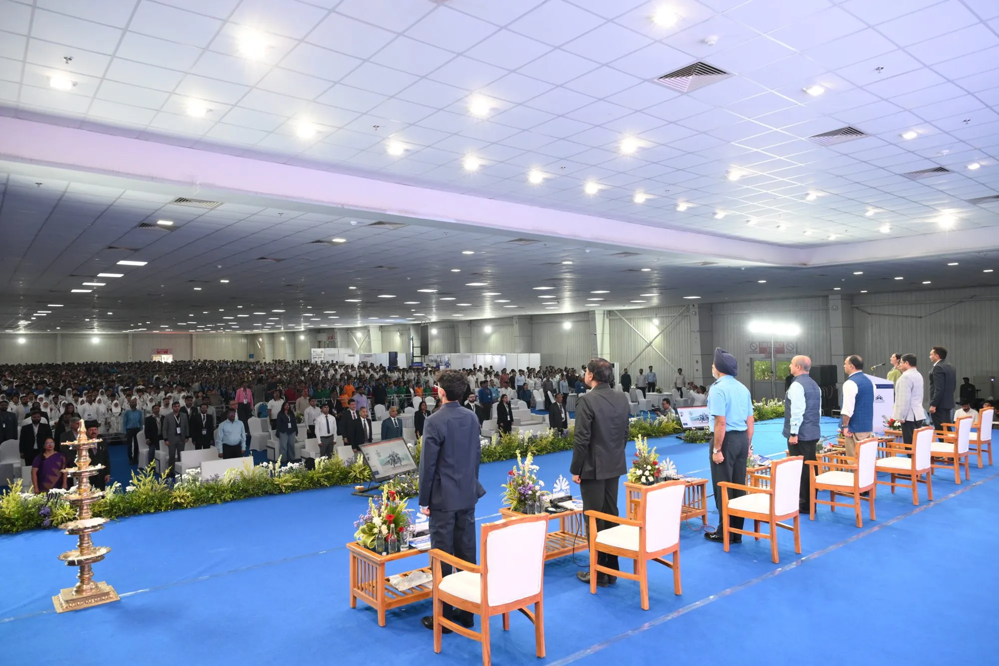 ASPIRE 2026: the hall on its feet, seen from the side of the stage, with the guests on the dais standing before the audience.